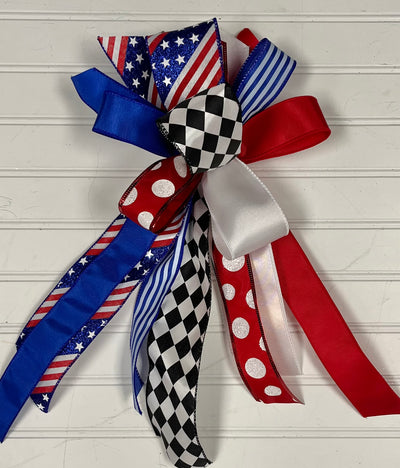 A small streamer bow with red, white, and blue ribbons with stars, stripes, and checkered patterns tied together.